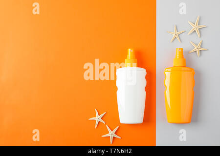 Flat lay composition with sunscreen sprays and starfishes on two tone background, space for text. Summer vacation backdrop Stock Photo