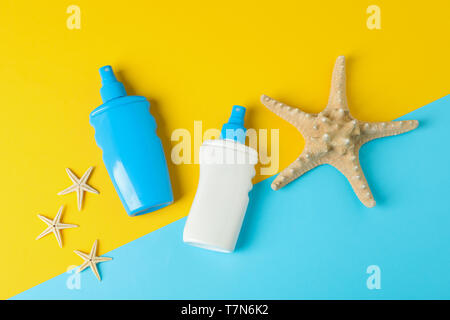 Flat lay composition with sunscreen sprays and starfishes on two tone background, space for text. Summer vacation backdrop Stock Photo