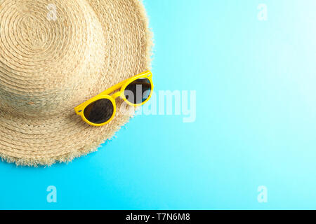 Straw hat and sunglasses on color background, space for text Stock Photo