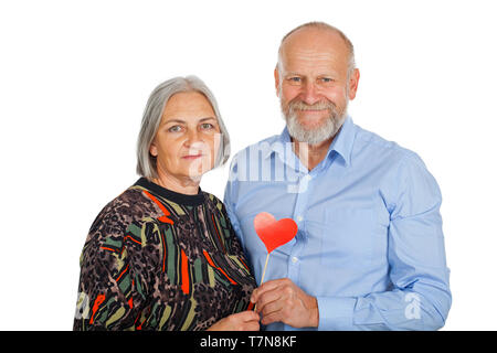 Senior couple holding red heart photo accessory, smiling to the camera on isolated background - romantic concept Stock Photo
