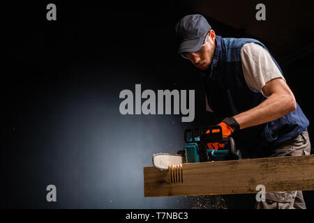 Handsome young man with modern electric chain saw in the workshops Stock Photo