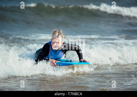 Mature woman having fun on a bodyboard in the sea. Stock Photo