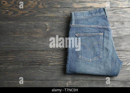 Blue jeans folded on a wooden background, space for text Stock Photo