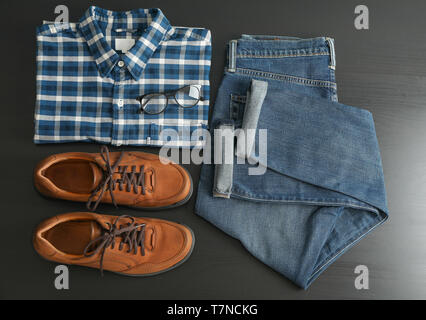 Flat lay composition with jeans, shirt, glasses and shoes on black table Stock Photo