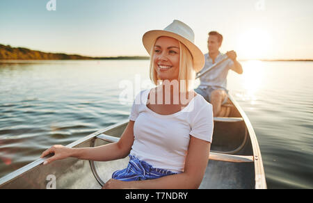 Smiling young couple enjoying a summer day paddling their canoe on a lake in the late afternoon