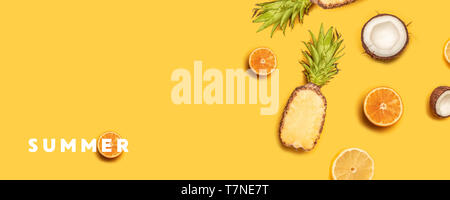 Pineapples, oranges, lemons, coconuts on yellow background. Summer fruits. Flat lay, top view, copy space Stock Photo