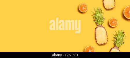 Pineapples, oranges, lemons, coconuts on yellow background. Summer fruits. Flat lay, top view, copy space Stock Photo