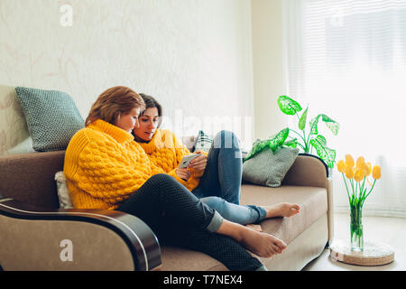 Senior mother and her adult daughter using smartphone at home. Mother's day concept. Stock Photo