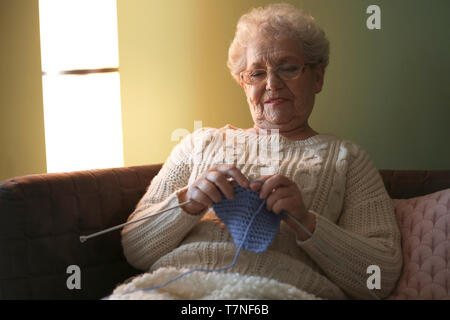 Senior woman knitting warm sock at home Stock Photo