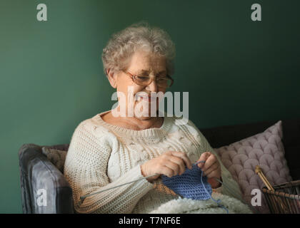 Senior woman knitting warm sock at home Stock Photo