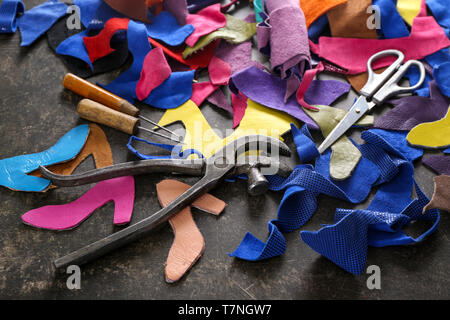 Pieces of colorful leather with craft tools on grey background Stock Photo