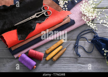 Colorful leather with craft tools and threads on wooden background Stock Photo