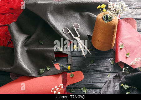 Pieces of colorful leather with thread and scissors on table Stock Photo