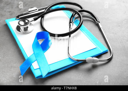 Blue ribbon, stethoscope and clipboard on grey background. Prostate cancer concept Stock Photo