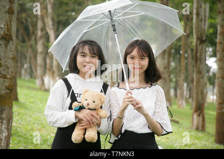 photo of two cute girls holding an umbrella Stock Photo