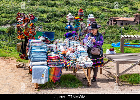 Chinchero, Peru – April 4, 2019: In Chinchero, Peru local woman selling traditional Peruvian clothes, textile handicraft and knits products made of Al Stock Photo