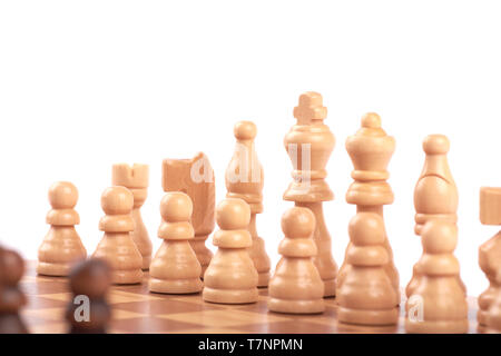 Set of white and black wooden chess pieces standing in a row on a chessboard, isolated on white background Stock Photo