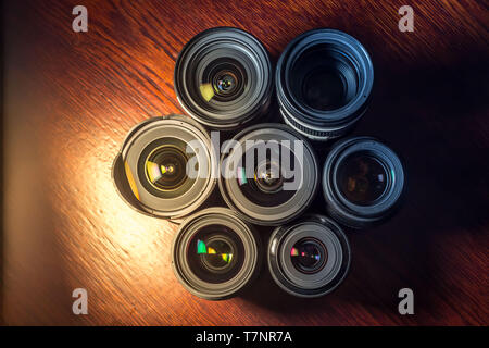 Set of various DSLR lenses with colorful reflections - shot from above on wooden background Stock Photo