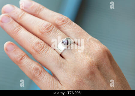 Female hand wearing silver ring with ruby star gemstone Stock Photo