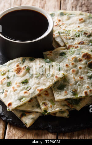 Delicious Chinese vegetarian onion pancakes served with sauce close-up on a board on the table. vertical Stock Photo