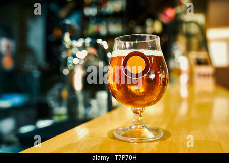 Selective focus of mug of tasty cold beer standing on table in pub. Frech alcoholic drink for clients in bar. Pint of ale standing on counter in evening in cafe. Concept of beverage and brewery. Stock Photo