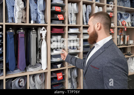 Man choosing new tie in clothing boutique Stock Photo - Alamy