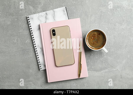 Cup of coffee with copybooks, phone and pen on grey background, top view Stock Photo