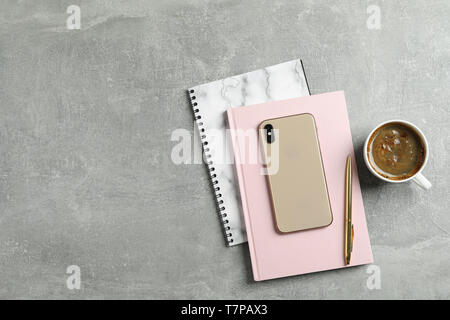 Cup of coffee with copybooks, phone and pen on grey background, top view Stock Photo