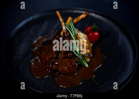rack of lamb on a black plate with garnish Stock Photo