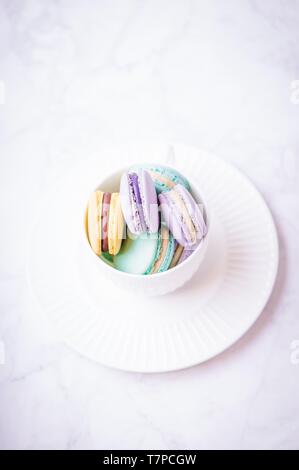 Sweet colourful pastel french macaroons or macaron on white marble background. Top view, copy space Stock Photo