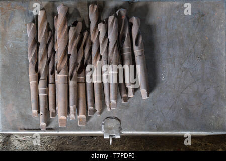 An assortment of metal drill in a row on a box in a train engineers workshop, the Mining Museum, Lake District, UK Stock Photo