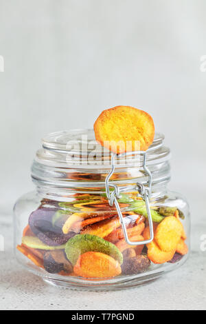 Colourful mix vegetable chips in glass jar, vertical composition Stock Photo