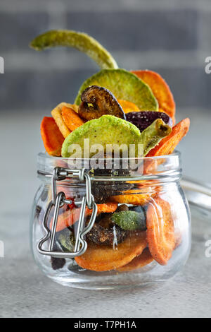 Colourful mix vegetable chips in glass jar, vertical composition Stock Photo
