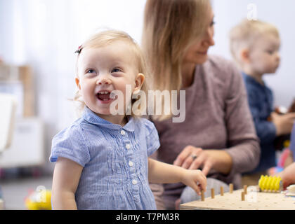 Babies in kindergarten. Kids toddlers in nursery school. Little children preschoolers playing with teacher. Stock Photo