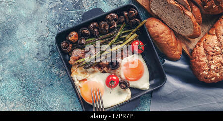 Food banner. Fried eggs with mushrooms and asparagus on a square griddle and bread. Breakfast. Top view Stock Photo