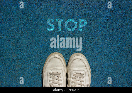 New life concept, Sport shoes and the word STOP written on blue walk way ground, Motivational slogan. Stock Photo