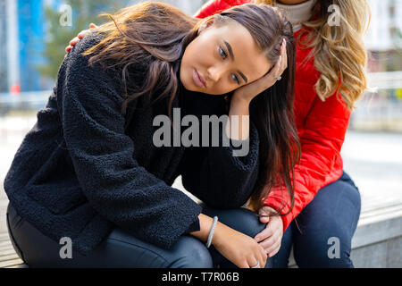 Friend Consoling Unhappy Young Woman In City Stock Photo