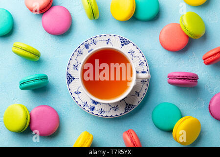 Macaroons dessert and cup of tea on blue background. Flat lay composition. Top view. Stock Photo