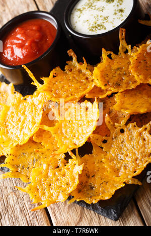 Delicious appetizer of cheddar cheese chips with herbs served with sauces close-up on the table. vertical Stock Photo