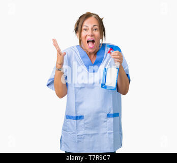 Middle age brunette cleaner woman wearing housework uniform over isolated background very happy and excited, winner expression celebrating victory scr Stock Photo