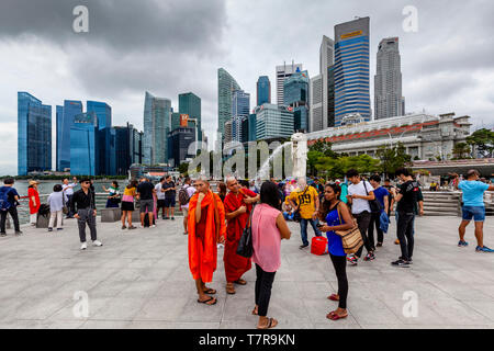 Tourists Posing For Photos In Front Of The Merlion Statue and Singapore Skyline, Singapore, South East Asia Stock Photo