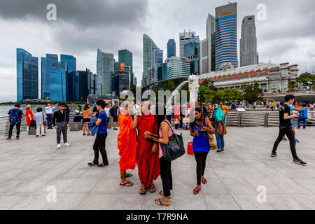 Tourists Posing For Photos In Front Of The Merlion Statue and Singapore Skyline, Singapore, South East Asia Stock Photo