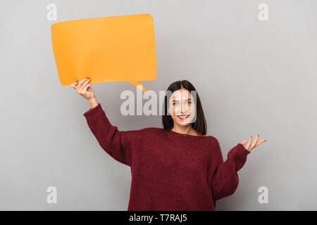 Portrait of joyful woman 30s holding blank placard for text isolated over gray background Stock Photo