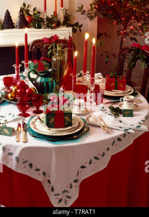 Colourfully gift wrapped presents on table set for Christmas dinner Stock Photo