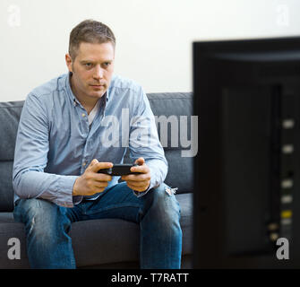 Handsome man playing video game at home. Stock Photo