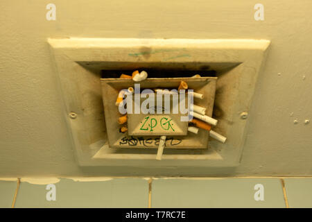 Used cigarettes butts stuck in airport public toilet ventilation as gross behaviour and illegal smoking at airport Stock Photo