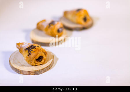 Croissants filled with chocolate on three wood planks. Isolated with white background Stock Photo