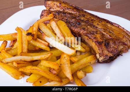 Sliced grilled pork ribs barbecue Striploin steak with chimichurri sauce and potato free on white plate. Stock Photo