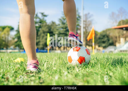 Young female soccer player traning with ball in the stadium - Sporty woman making exercises on the train field Stock Photo