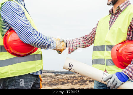 Builders shaking hands making an agreement on costruction site - Workers reaching a deal on renewable energy project on the working site Stock Photo